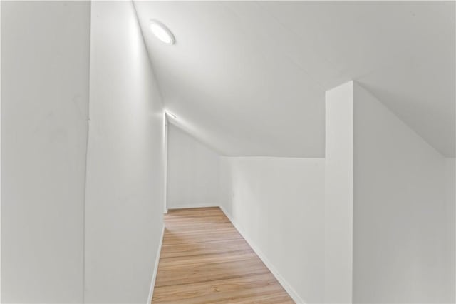 interior space with vaulted ceiling, light wood-style floors, and baseboards