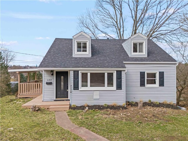 new england style home featuring a front lawn and roof with shingles