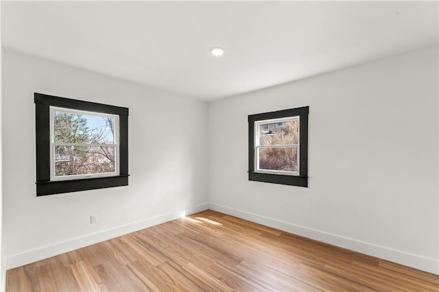 unfurnished room featuring a wealth of natural light, light wood-type flooring, and baseboards