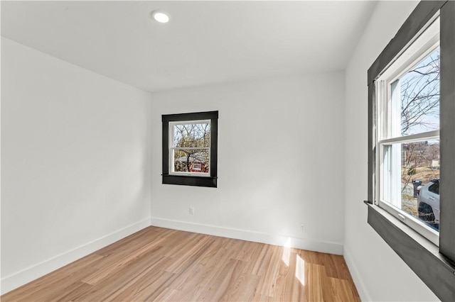 empty room with baseboards, plenty of natural light, and light wood-style flooring