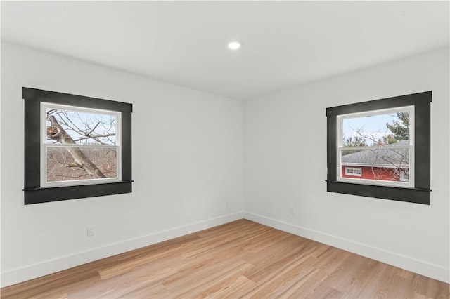 empty room with plenty of natural light, light wood-style flooring, and baseboards