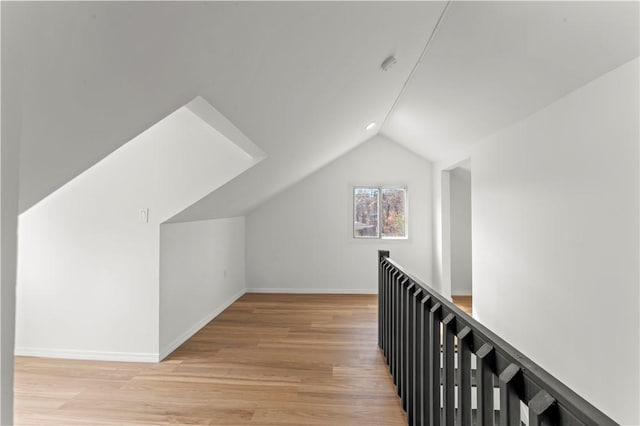 bonus room featuring light wood finished floors, baseboards, and lofted ceiling