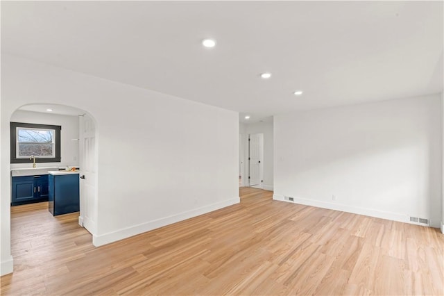 unfurnished room with visible vents, baseboards, light wood-style flooring, recessed lighting, and arched walkways