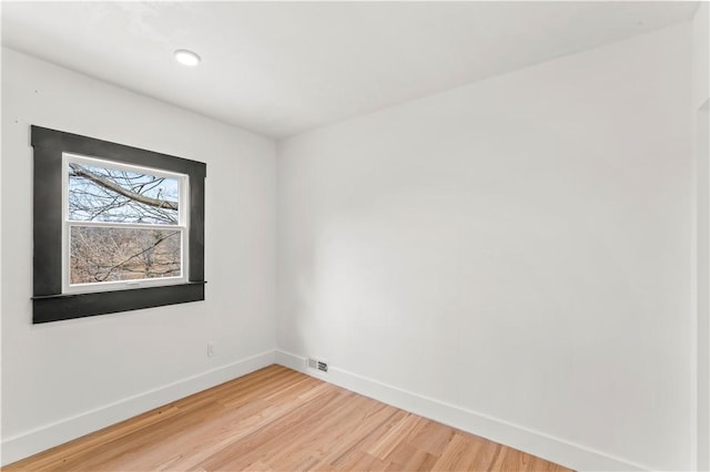 spare room with baseboards and light wood finished floors