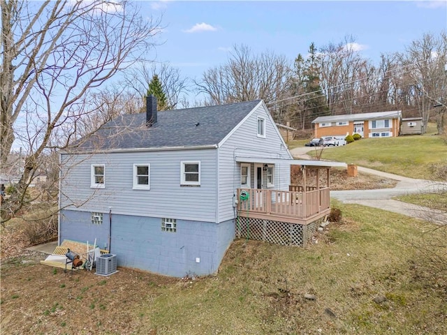 rear view of property featuring a yard, central AC unit, roof with shingles, and a chimney