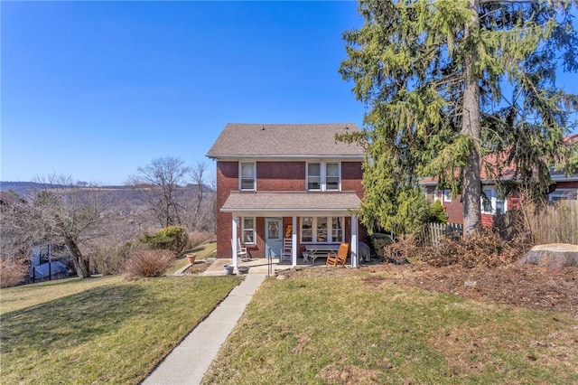 view of front of house with a front yard, brick siding, and covered porch