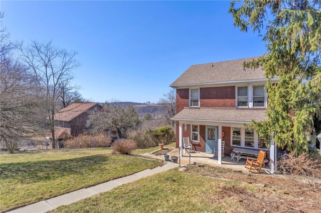 view of front of property with a front yard, a patio area, and brick siding