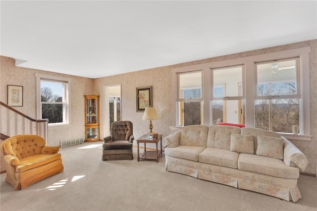 living room featuring wallpapered walls, stairs, carpet, and visible vents