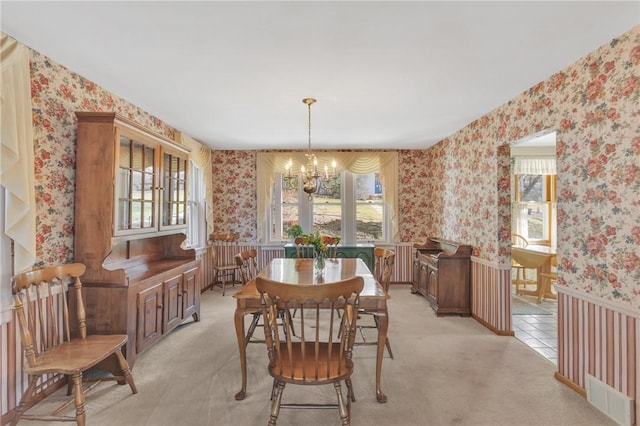 dining room with light carpet, a notable chandelier, wallpapered walls, and visible vents