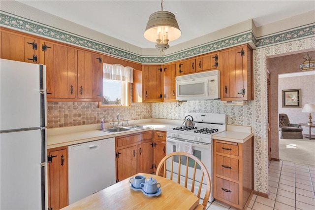 kitchen with white appliances, wallpapered walls, light countertops, and a sink