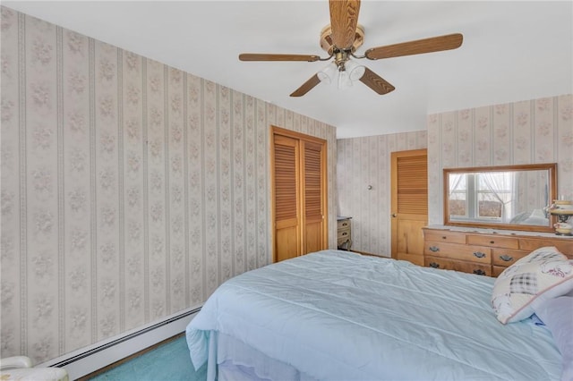 bedroom with a baseboard heating unit, a closet, a ceiling fan, and wallpapered walls