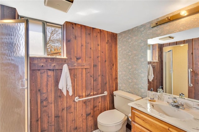 full bathroom featuring wallpapered walls, toilet, vanity, and a stall shower