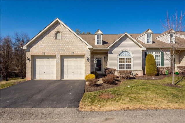 view of front of property with brick siding, driveway, an attached garage, and a front yard