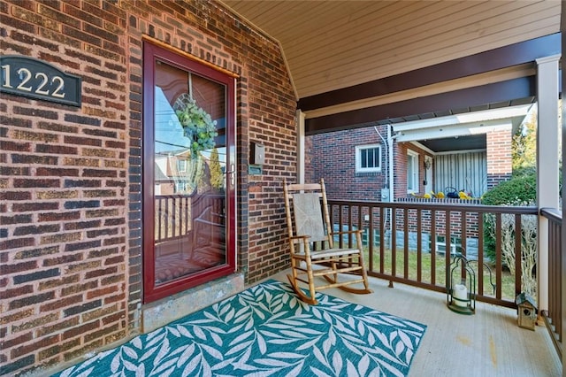 view of exterior entry featuring brick siding and covered porch