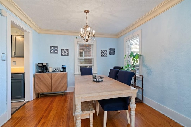 dining space featuring baseboards, a notable chandelier, wood finished floors, and ornamental molding