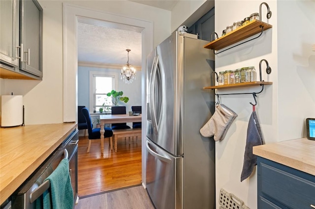 kitchen with butcher block countertops, light wood-style flooring, freestanding refrigerator, an inviting chandelier, and open shelves