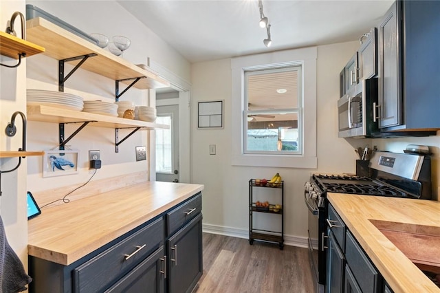 kitchen with dark wood-style floors, butcher block countertops, appliances with stainless steel finishes, and open shelves