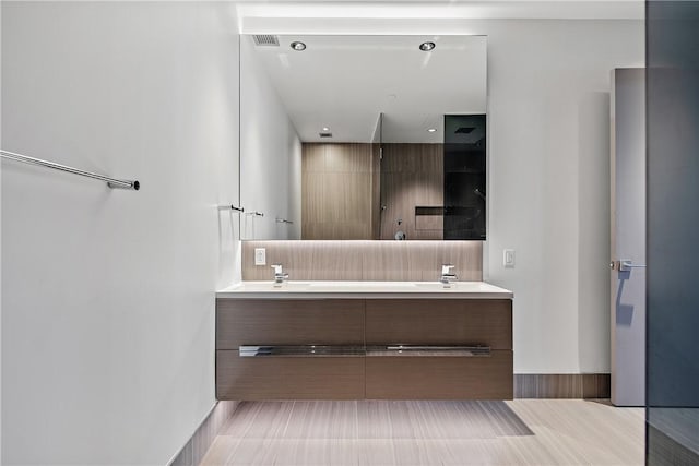 bathroom with double vanity, visible vents, a shower, and a sink