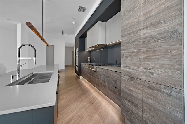 kitchen featuring visible vents, a sink, light countertops, light wood-style floors, and modern cabinets