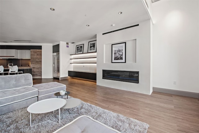 living room with a glass covered fireplace, recessed lighting, wood finished floors, and baseboards