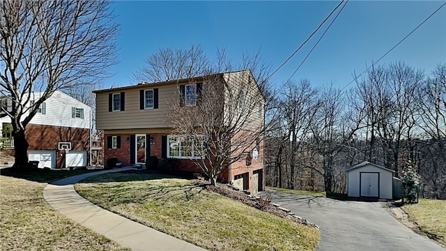 colonial inspired home with brick siding, a shed, aphalt driveway, and a front lawn