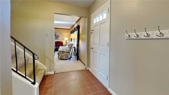 carpeted entrance foyer with tile patterned floors, baseboards, and stairs