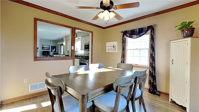 dining space with visible vents, crown molding, ceiling fan, baseboards, and light wood-type flooring