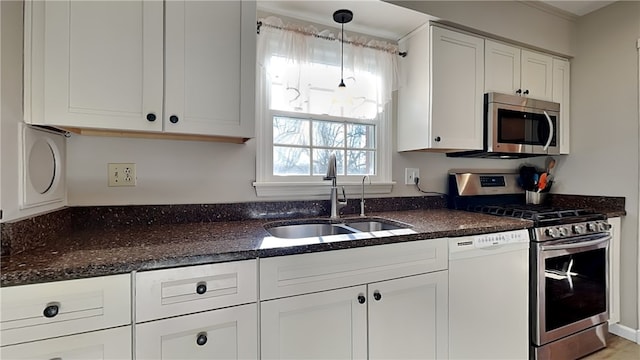 kitchen with pendant lighting, dark stone countertops, appliances with stainless steel finishes, white cabinetry, and a sink