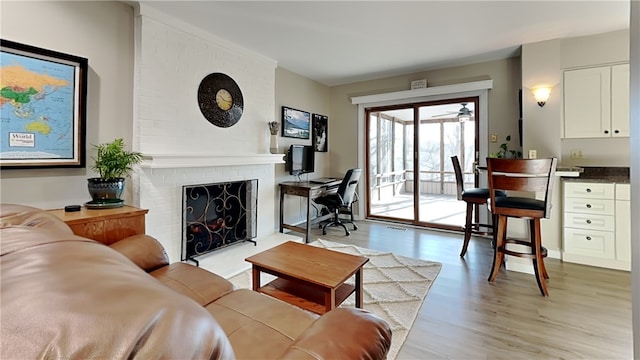 living area with light wood-style flooring and a brick fireplace