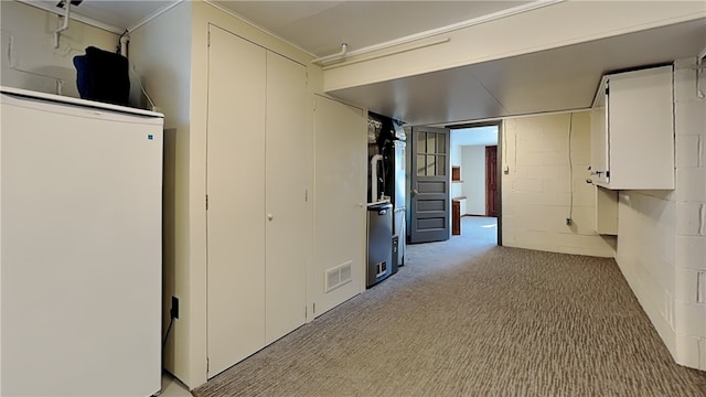 hallway with visible vents, light colored carpet, and concrete block wall