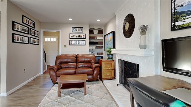 living room with light wood-type flooring, recessed lighting, stairway, baseboards, and a brick fireplace