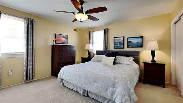 bedroom featuring a closet, visible vents, light colored carpet, and a ceiling fan