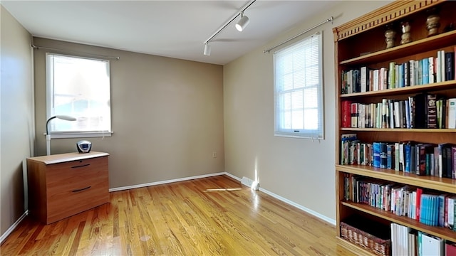 living area featuring baseboards, light wood-style floors, and track lighting