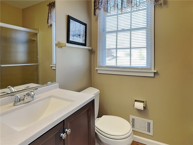 bathroom featuring vanity, a shower stall, toilet, and visible vents