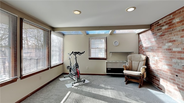 exercise room with a wealth of natural light, brick wall, baseboards, and carpet floors