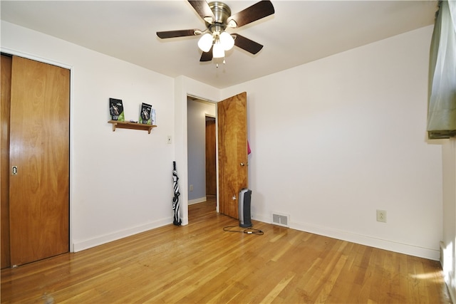 unfurnished bedroom featuring a ceiling fan, visible vents, baseboards, light wood-style floors, and a closet