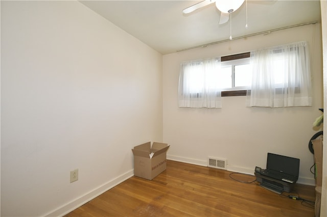 empty room with ceiling fan, visible vents, baseboards, and wood finished floors