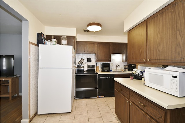 kitchen featuring black appliances, a sink, backsplash, light countertops, and light tile patterned floors