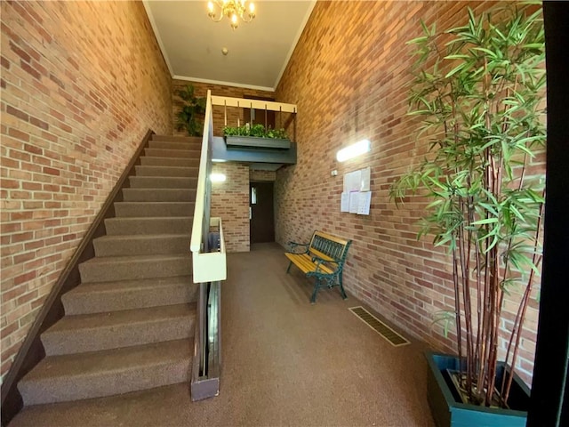 stairs with visible vents, brick wall, carpet, and ornamental molding