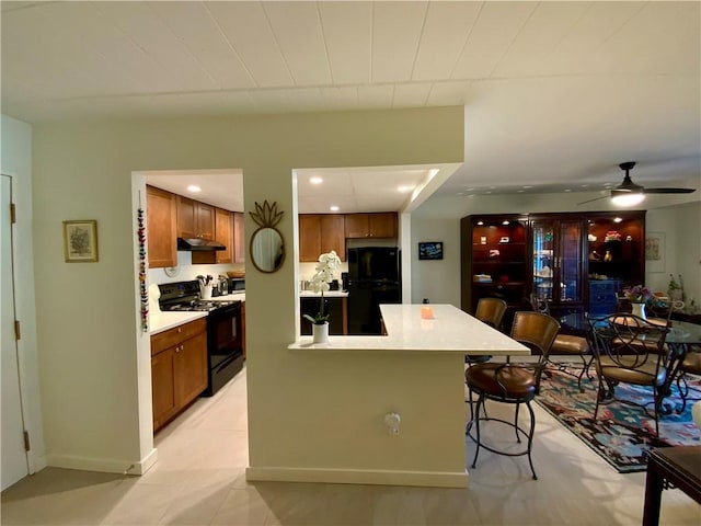 kitchen featuring black appliances, a kitchen breakfast bar, light countertops, and brown cabinets