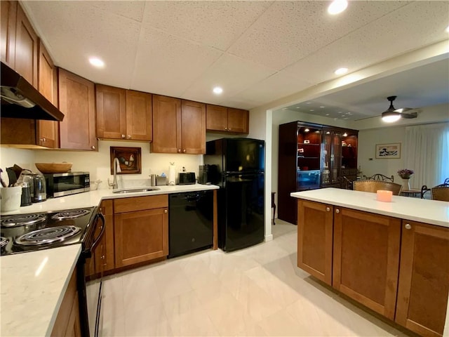 kitchen featuring brown cabinets, black appliances, light countertops, and a sink