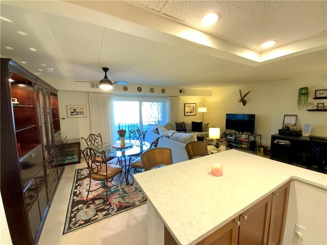 kitchen with open floor plan, light countertops, recessed lighting, a raised ceiling, and a ceiling fan