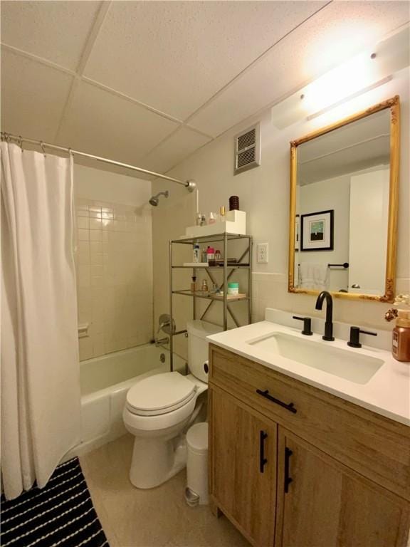 bathroom with visible vents, toilet, shower / bath combo, a drop ceiling, and vanity