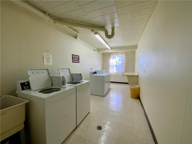 common laundry area with washing machine and clothes dryer, light floors, baseboards, and a sink