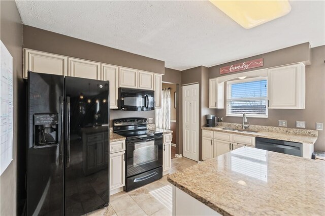 kitchen featuring light stone counters, a sink, black appliances, a textured ceiling, and white cabinetry