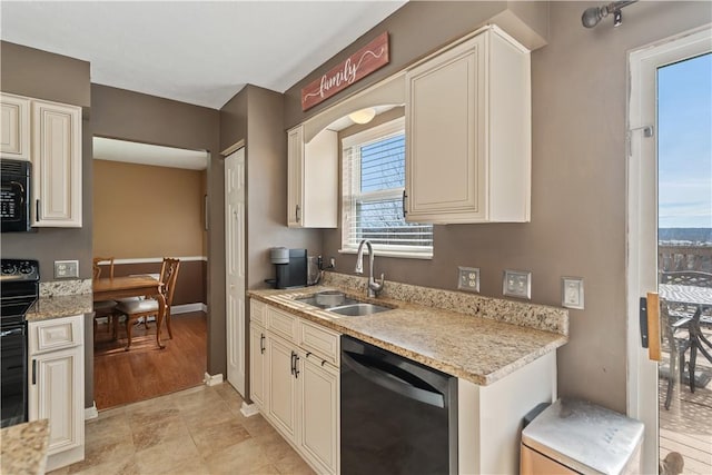 kitchen with black appliances, cream cabinetry, a sink, baseboards, and light stone countertops