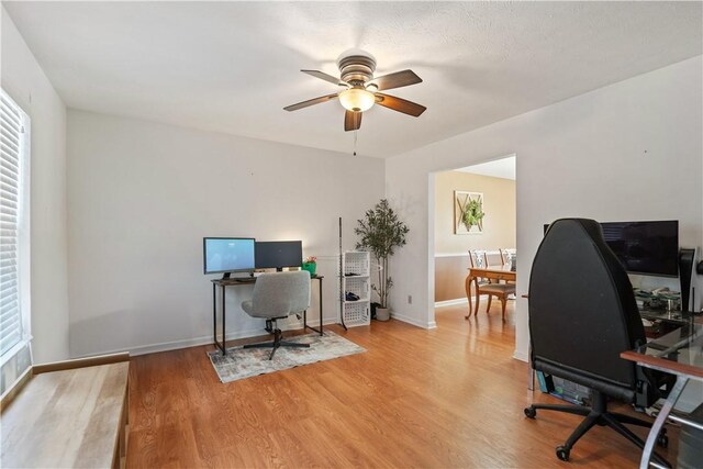 home office with a ceiling fan, light wood-style floors, baseboards, and a healthy amount of sunlight