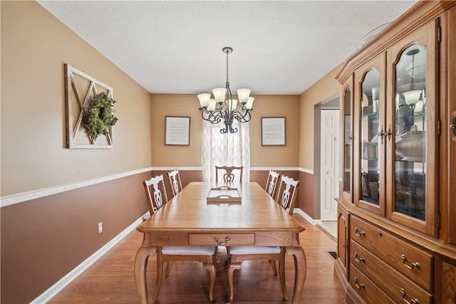 dining space with a notable chandelier, light wood-style flooring, and baseboards