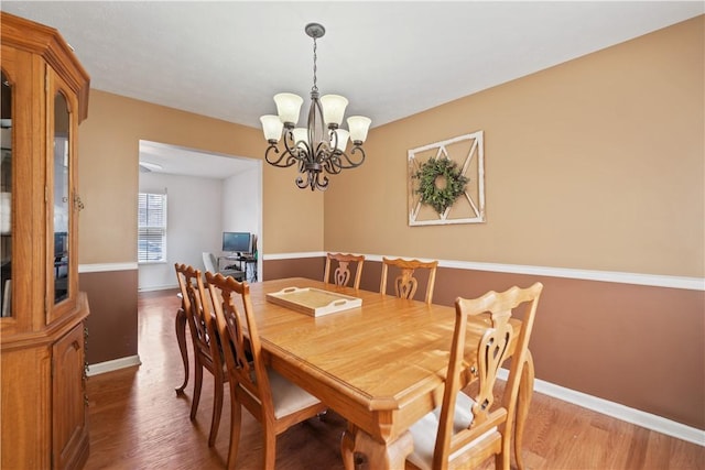 dining room with an inviting chandelier, baseboards, and wood finished floors