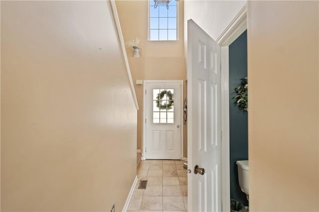 doorway featuring light tile patterned flooring and baseboards